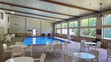 Relax by the pool with a clear view through large windows, surrounded by comfortable seating and tables.