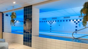 Ein modernes Hallenbad mit blau gefliesten Wänden und einer klaren Glasdecke.