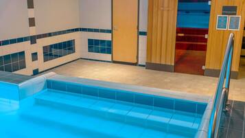 A pool area with a tiled floor, a wooden door, and a sign indicating an infrared sauna.