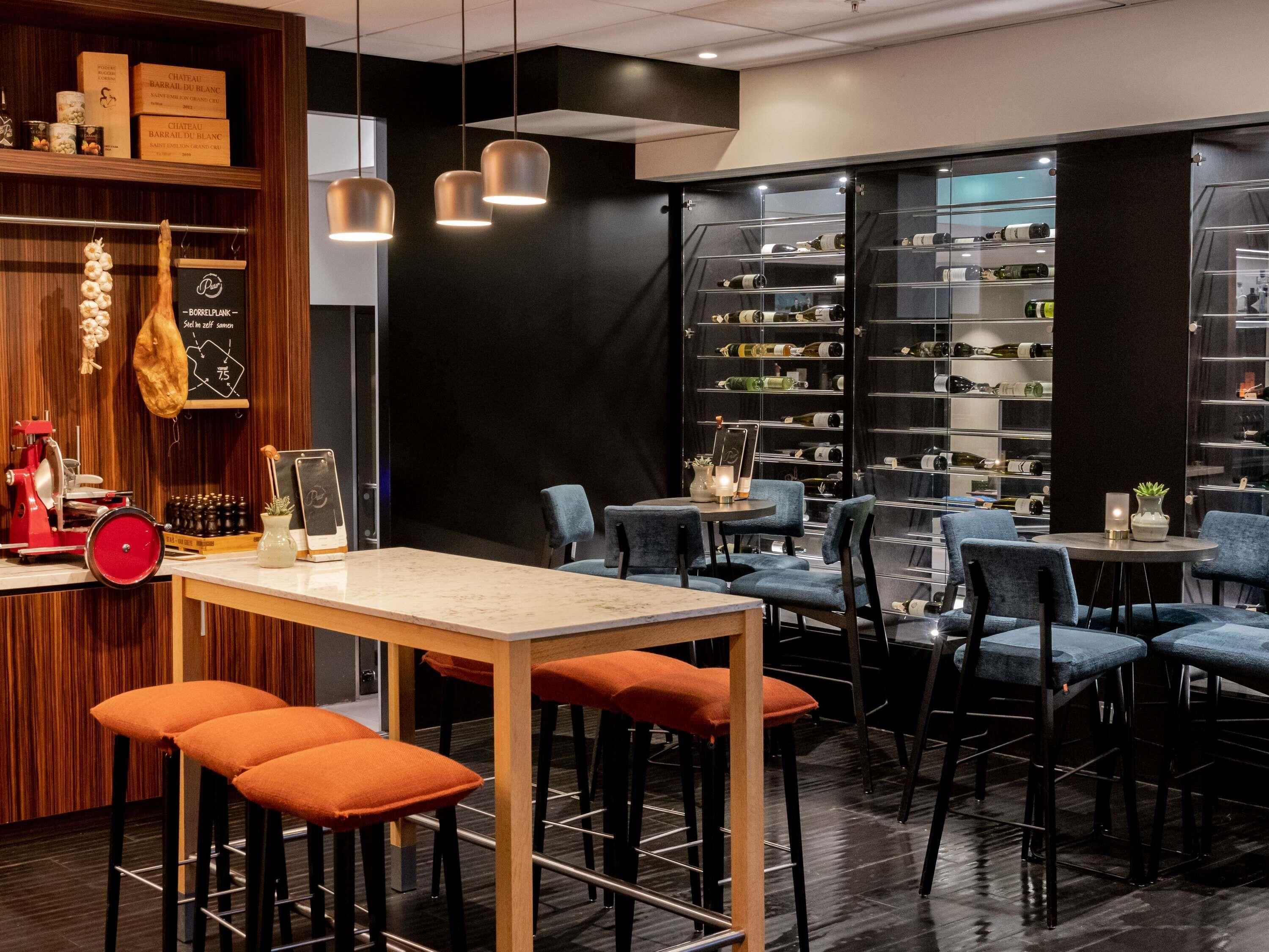 Un área de bar moderna con una cava de vinos, asientos y una barra.