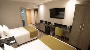 Una habitación de hotel con dos camas, un escritorio, una silla, un televisor y un armario.