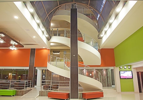 A multi-level atrium with a central spiral staircase, seating areas, and a digital display.