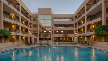 Una piscina al aire libre, sombrillas, sillones reclinables de piscina