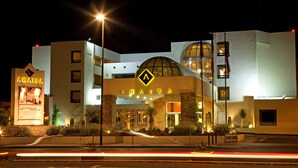 Un hotel con una entrada destacada, un cartel grande con un logotipo y una fachada bien iluminada.