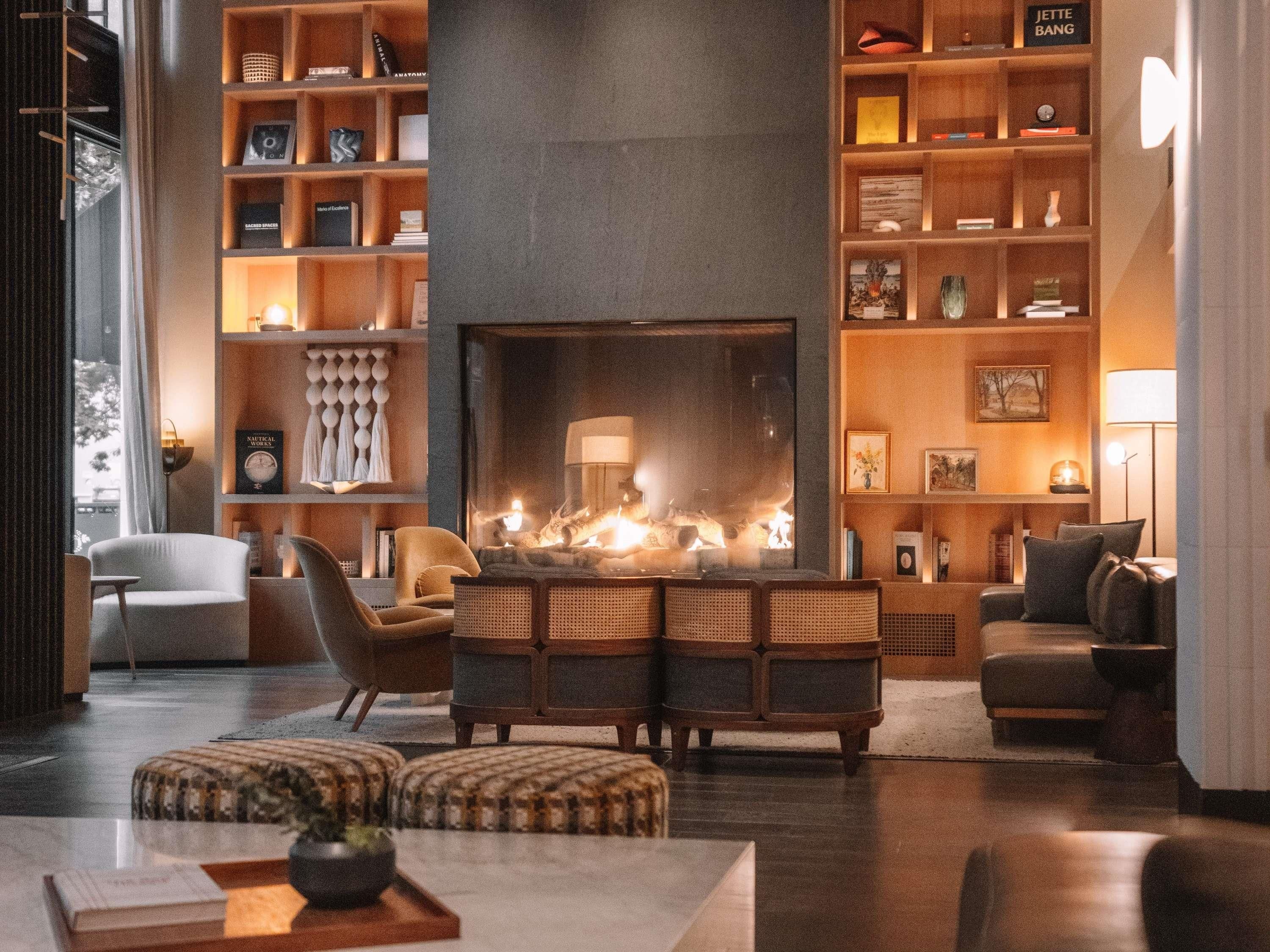A modern living room with a fireplace, comfortable seating, and a bookshelf filled with books and decorative items.