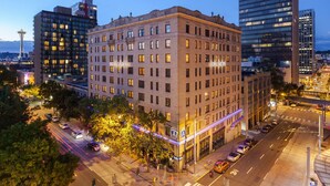 A multi-story hotel with a classic brick facade, large windows, and a prominent sign. - Ändra Hotel Seattle - MGallery Collection (Seattle)