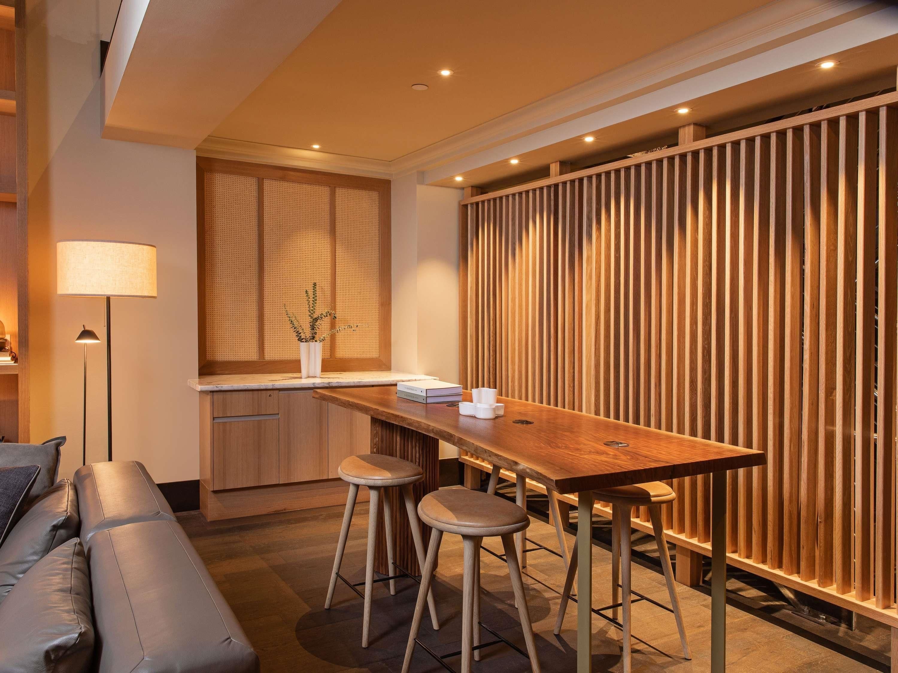 Una cocina moderna con encimera de madera, taburetes y un separador de madera integrado.
