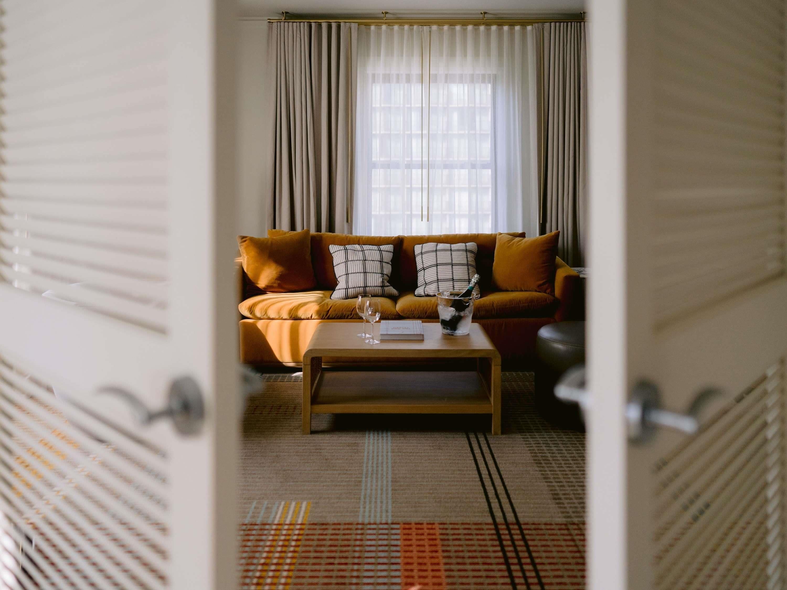 An open doorway to a living room with a sofa, pillows, a glass of water, and a book on a coffee table.