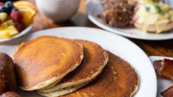 A breakfast setting with pancakes, sausages, and a cup of coffee.