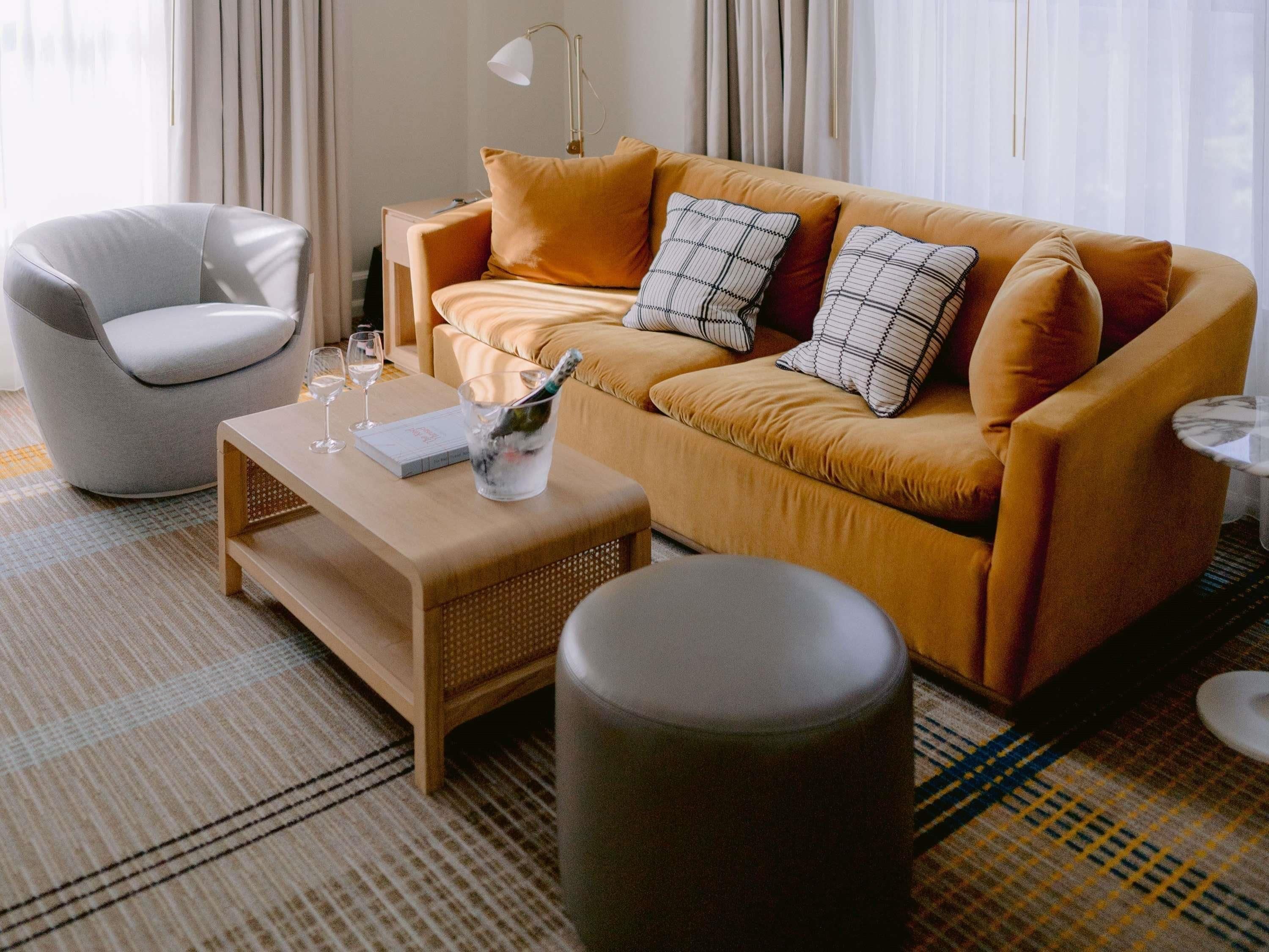 Una sala de estar moderna con sofá, sillón, mesa de centro y una mesita auxiliar.