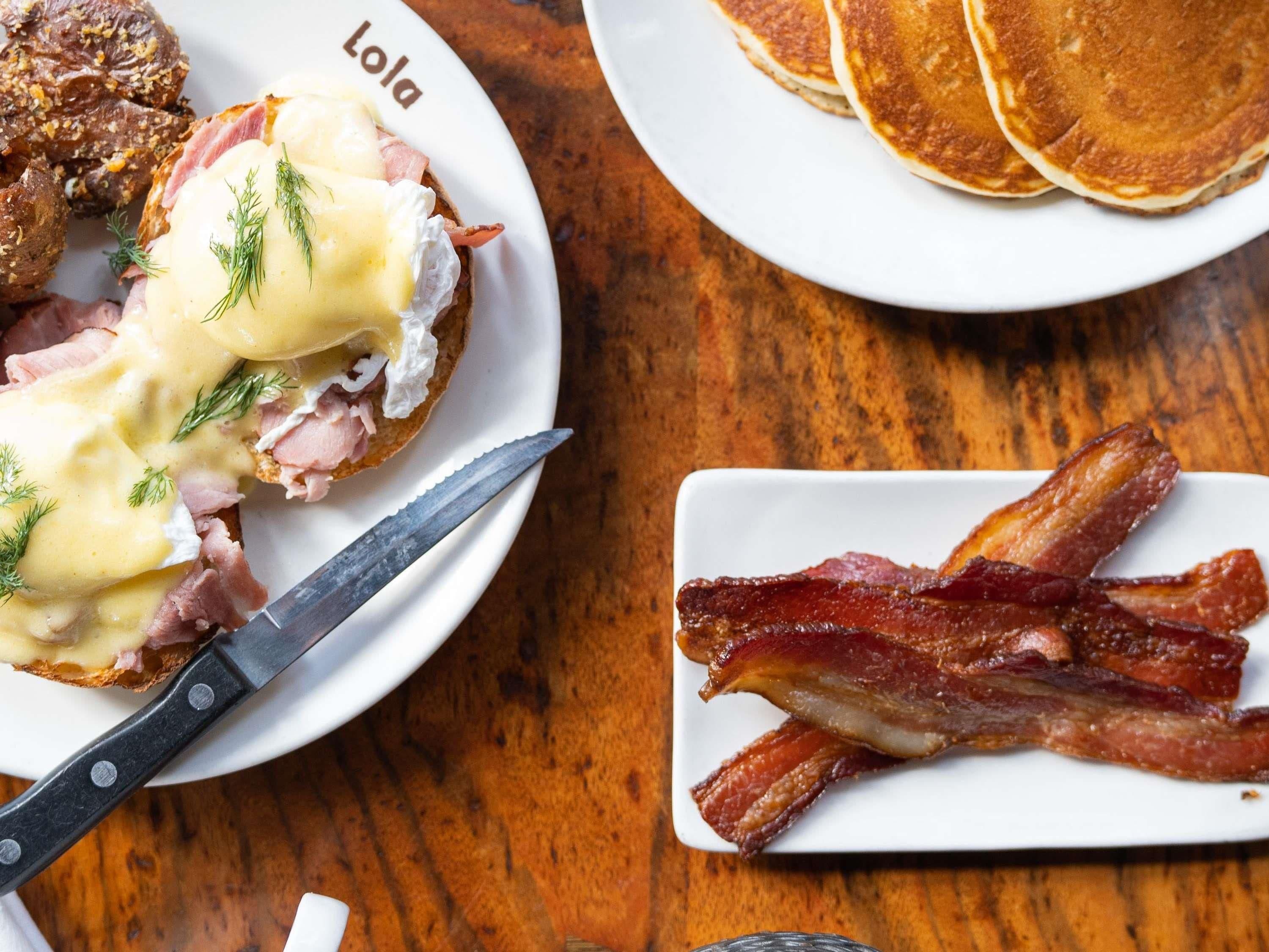 A breakfast plate with eggs Benedict, bacon, and toast.