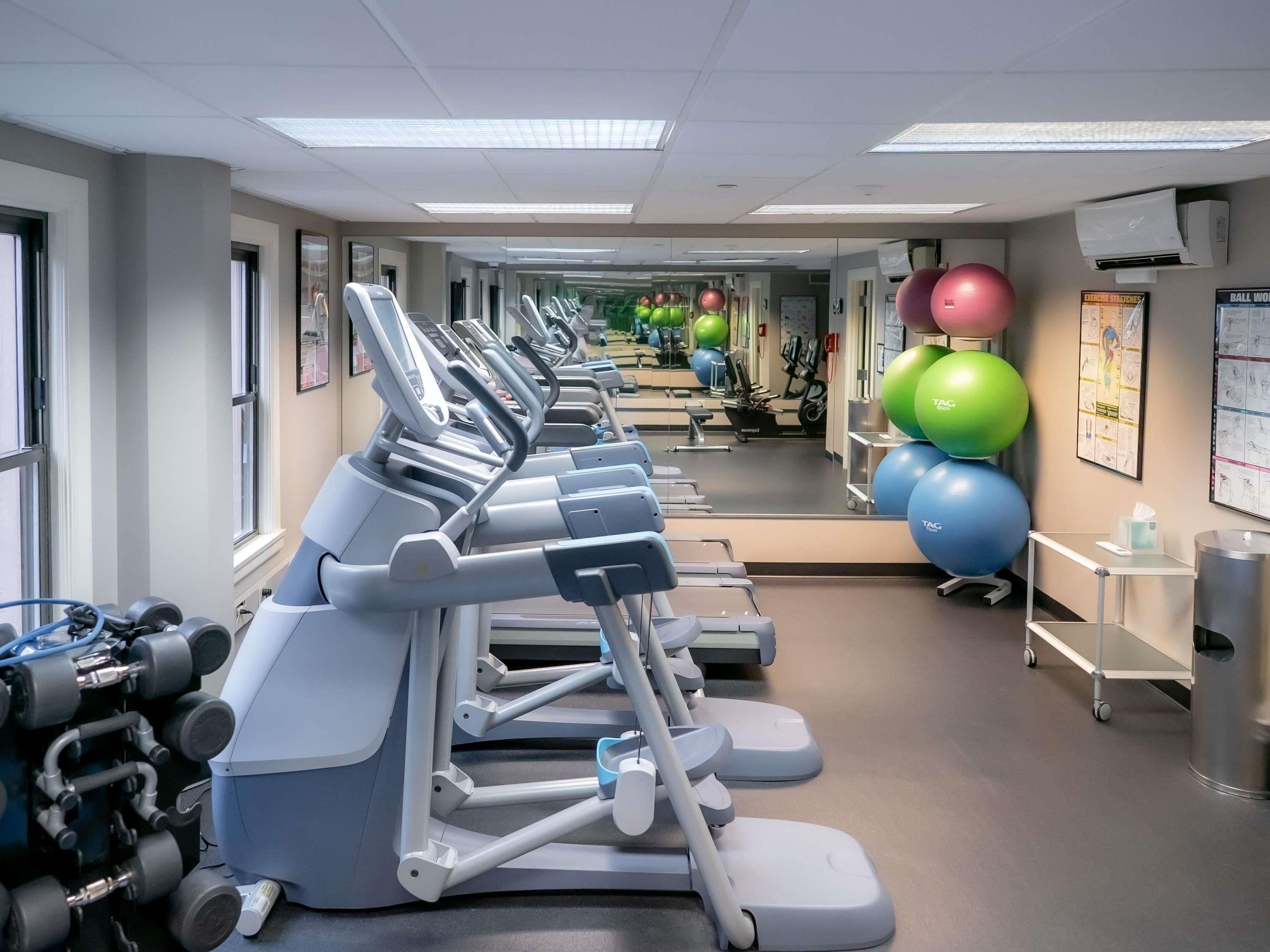 Un gimnasio con cintas de correr, pelotas de ejercicios y máquinas de pesas.