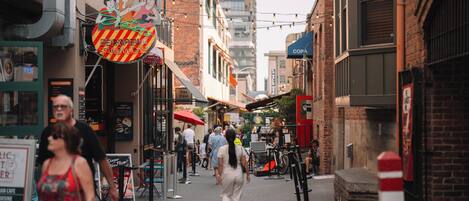 A narrow street lined with buildings, some with visible signage and awnings.