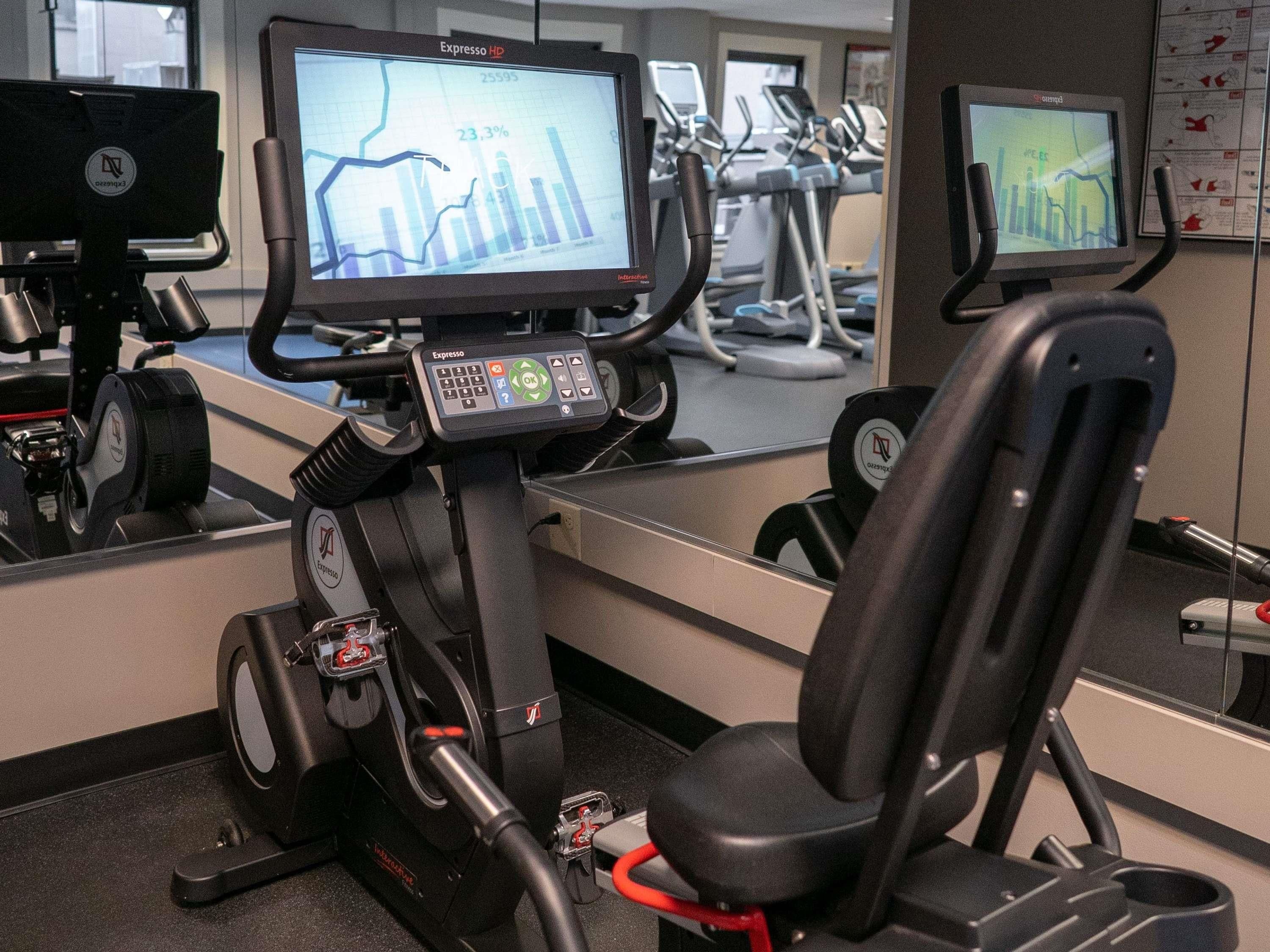 An exercise machine with a digital display, a chair, and a control panel.