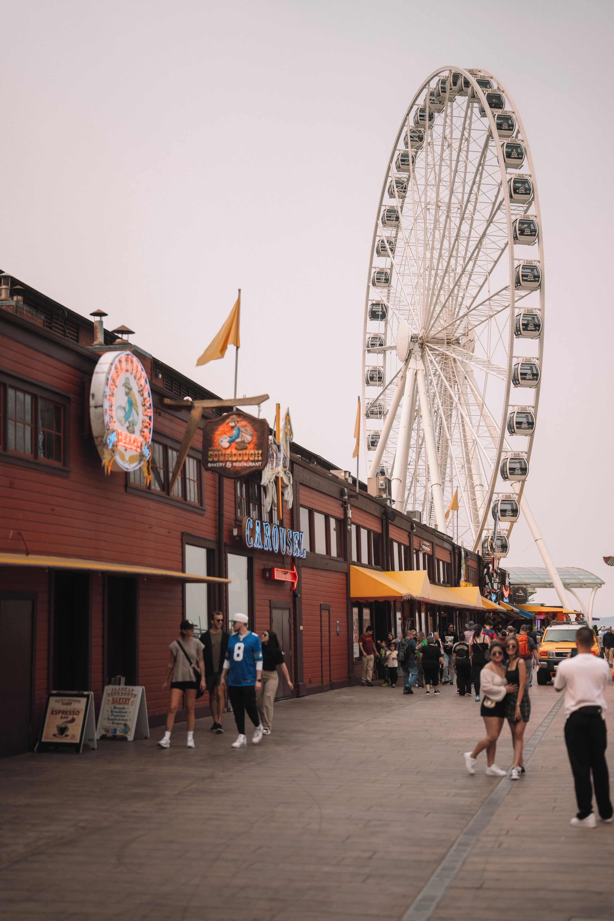 Una calle con una noria grande, un carrusel y un edificio con un letrero que dice 'CAROUSEL'.