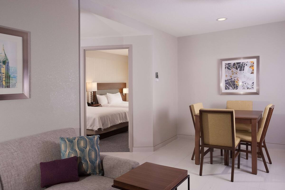A hotel room with a bed, a dining table with chairs, a sofa, and a coffee table.