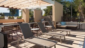 An outdoor patio with lounge chairs, a barbecue area, and a seating area with a sofa. - Home2 Suites by Hilton Atlanta Perimeter Center (Atlanta)