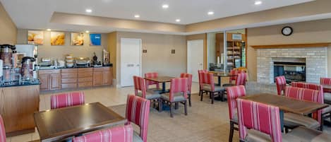 A hotel lobby with a coffee station, seating area, and a fireplace.