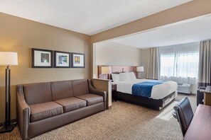 A hotel room with a bed, a sofa, a desk, and a chair. - Comfort Suites Normal University area (Normal)