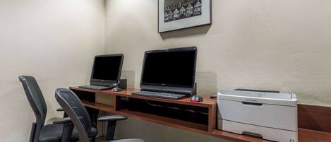 A workspace with two laptops, a printer, and two office chairs.