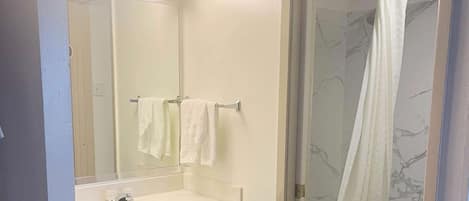 A bathroom with a white sink, mirror, and shower curtain.