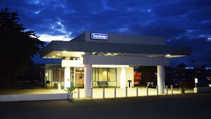 Un hotel Travelodge con diseño moderno, que presenta un letrero destacado, un acceso cubierto y una banca en el exterior.