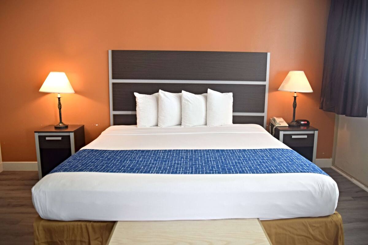 A hotel room with a large bed, two bedside tables with lamps, and a wooden headboard.
