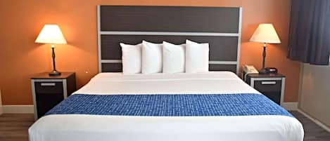 A hotel room with a large bed, two bedside tables with lamps, and a wooden headboard.