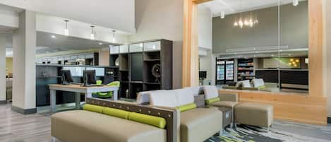 Un interior moderno con una zona de estar, un rincón de cocina y un espejo grande que refleja el ambiente.