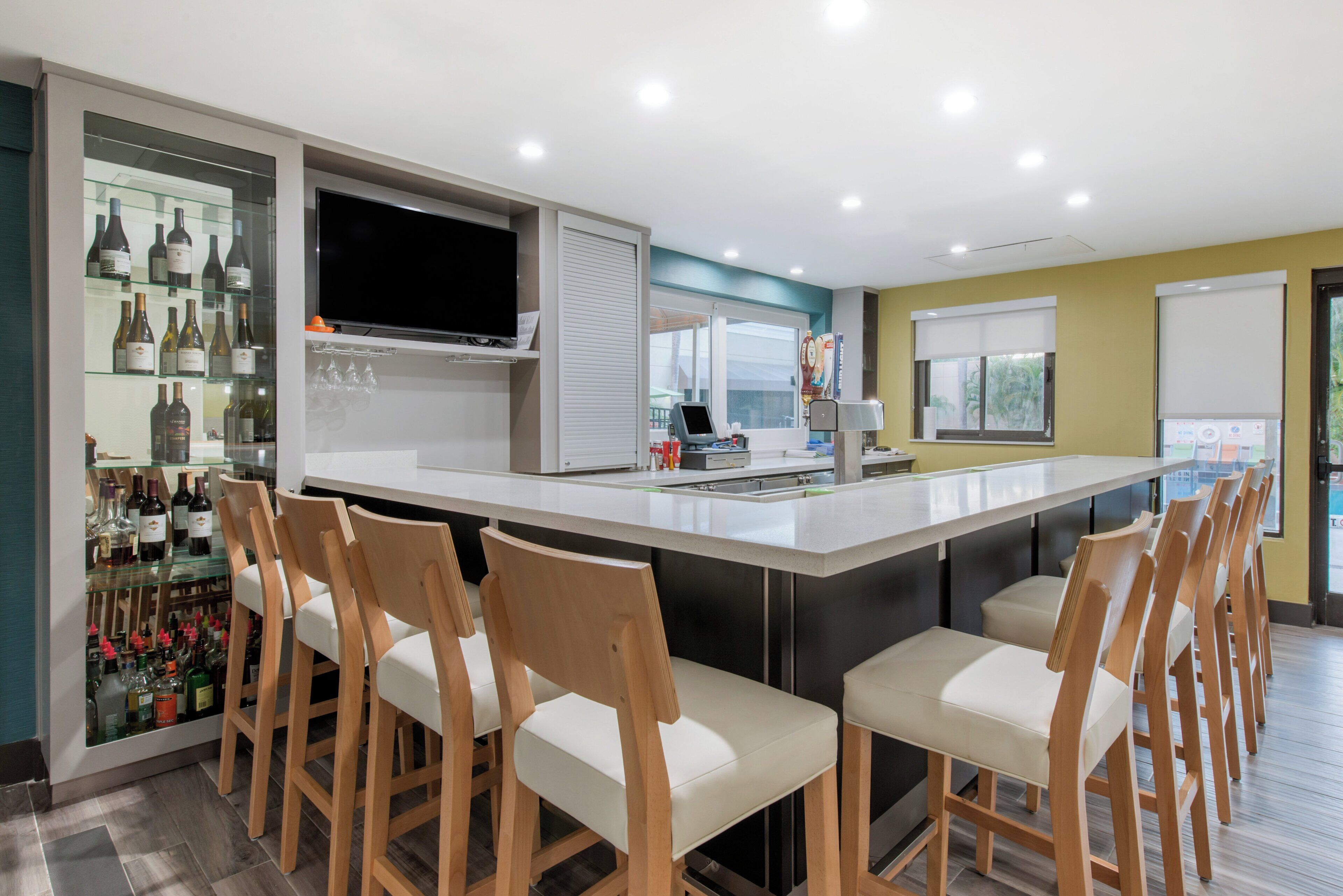 Una cocina moderna con barra, sillas de madera y un espacio para exhibir vino.