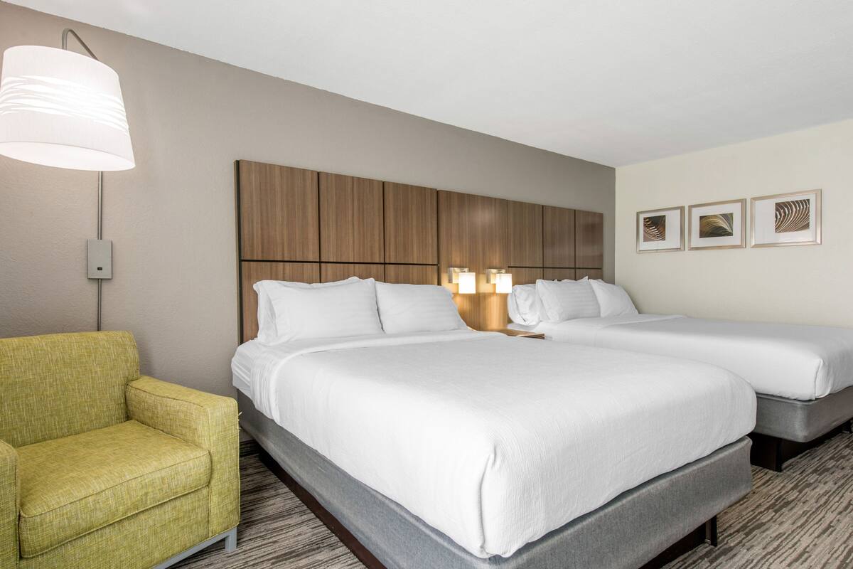A hotel room with a large bed, a small sofa, and a wall-mounted lamp.