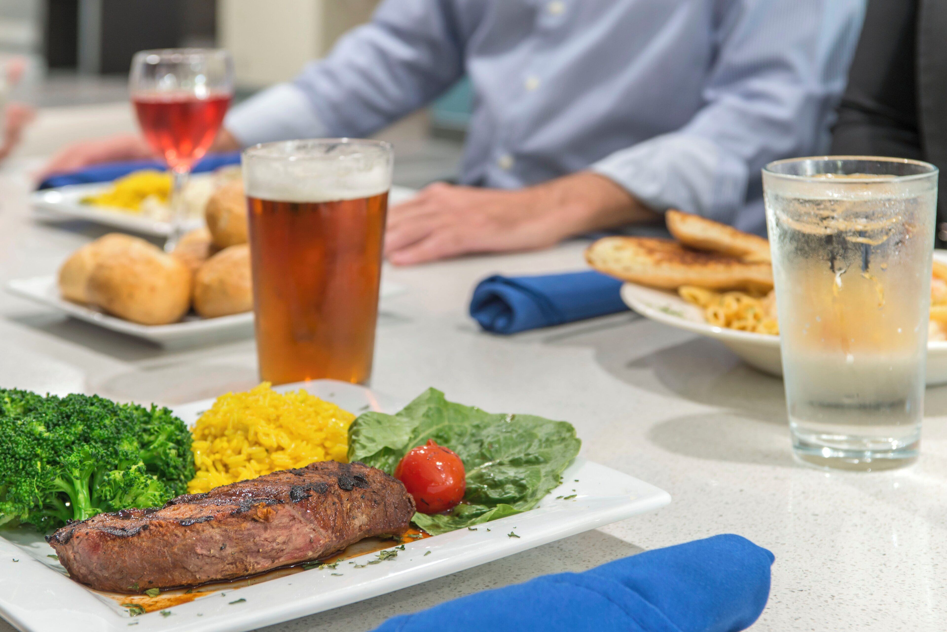 Una mesa de comedor con un plato de comida, una jarra de cerveza y un vaso de agua.