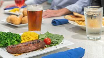 Una mesa de comedor con un plato de comida, una jarra de cerveza y un vaso de agua.
