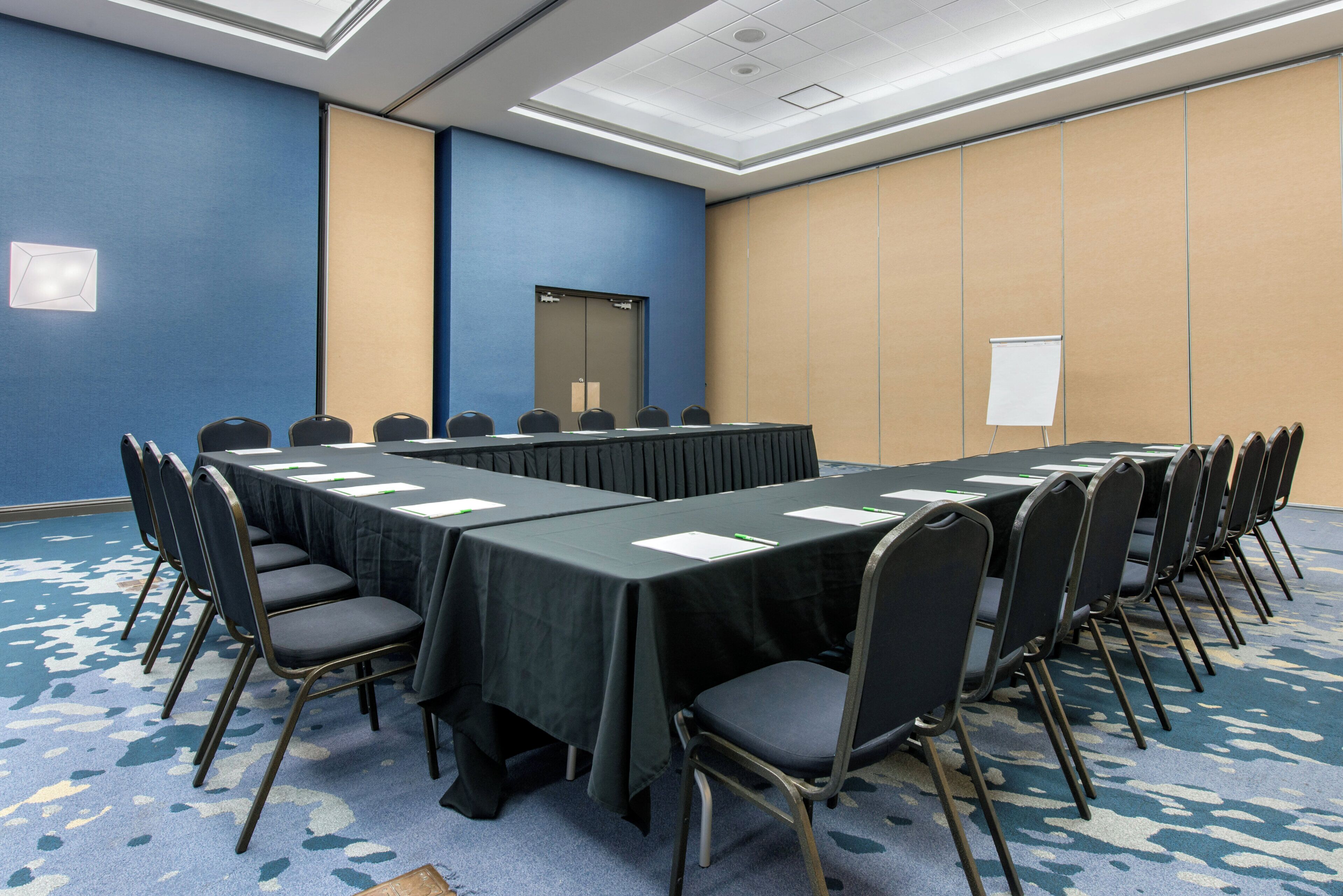 Un salón de conferencias con una larga mesa y sillas, una pizarra y una puerta.