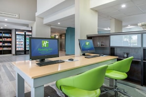 A modern office space with two computer monitors, a keyboard, and green chairs. - Holiday Inn Melbourne-Viera Conference Ctr by IHG (Melbourne)