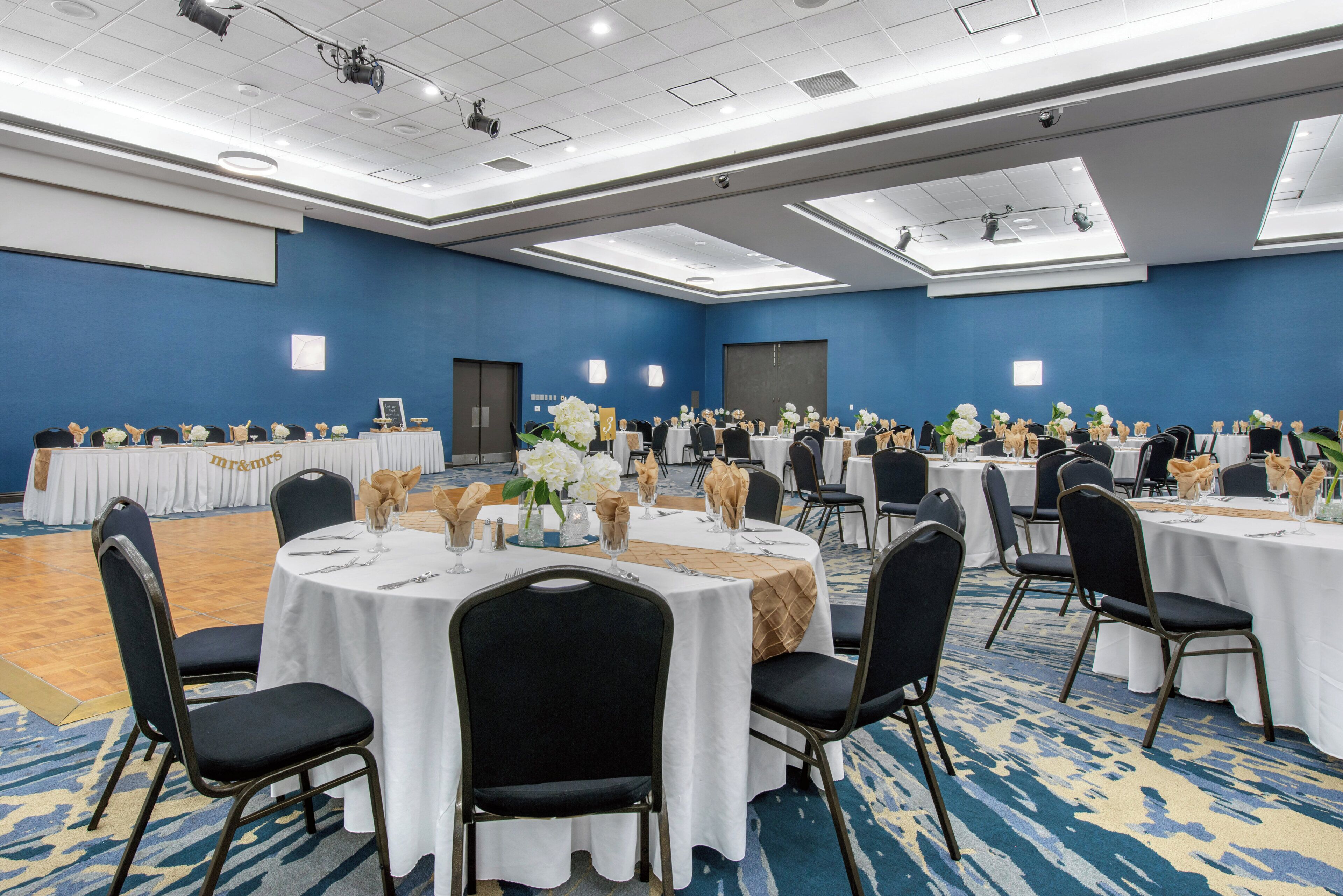 A conference room with round tables, chairs, and floral centerpieces.