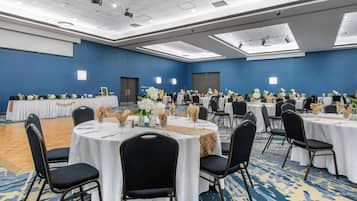 A conference room with round tables, chairs, and floral centerpieces.