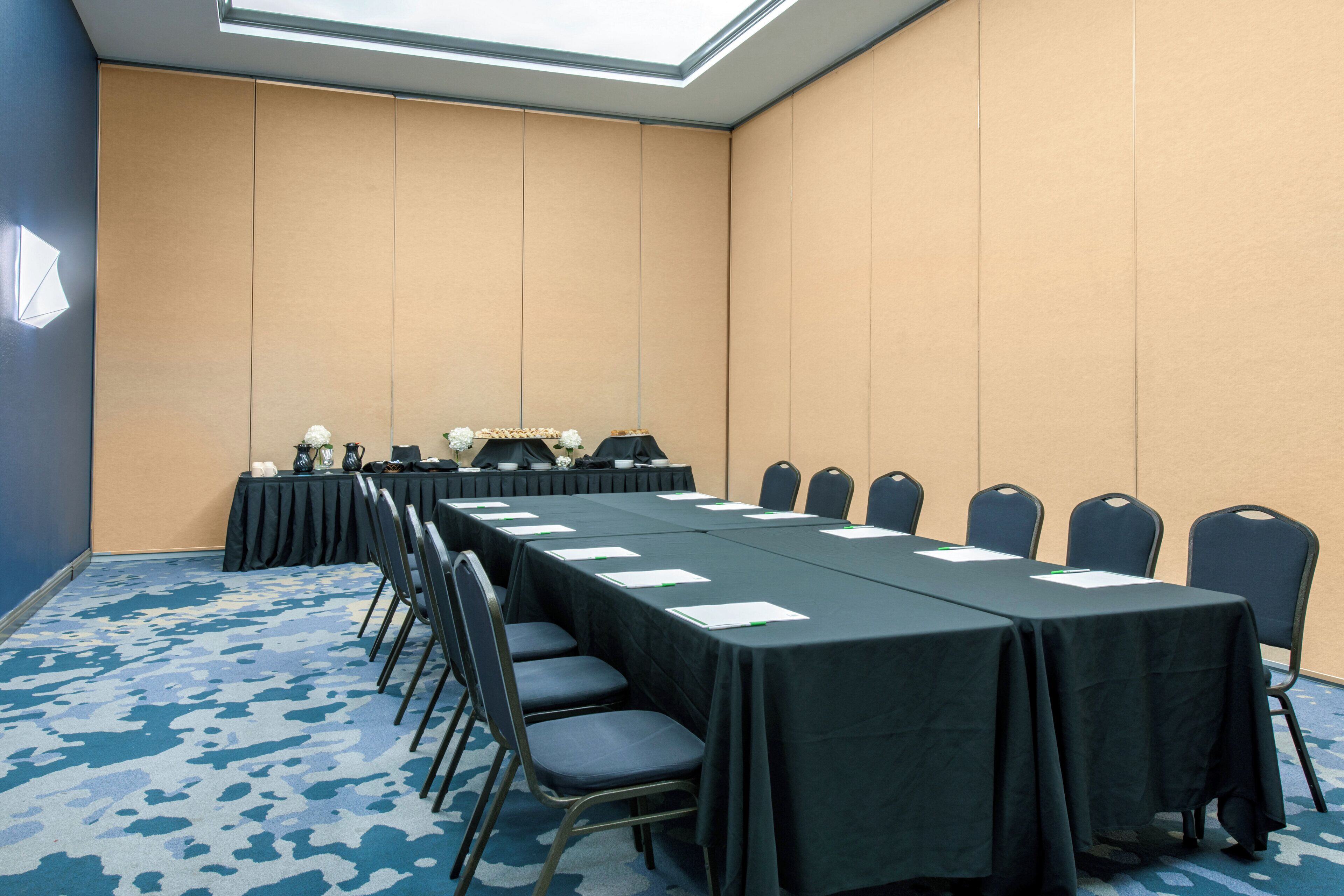 A conference room with a long table, chairs, and a small table with refreshments.