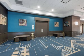 A hotel lobby with a blue carpet, artwork on the walls, a bench, and a door labeled 'EGRET ROOM'. - Holiday Inn Melbourne-Viera Conference Ctr by IHG (Melbourne)