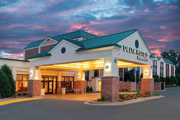 A Delta Hotels Marriott building with a brick facade, large entrance doors, and a covered area with lights.