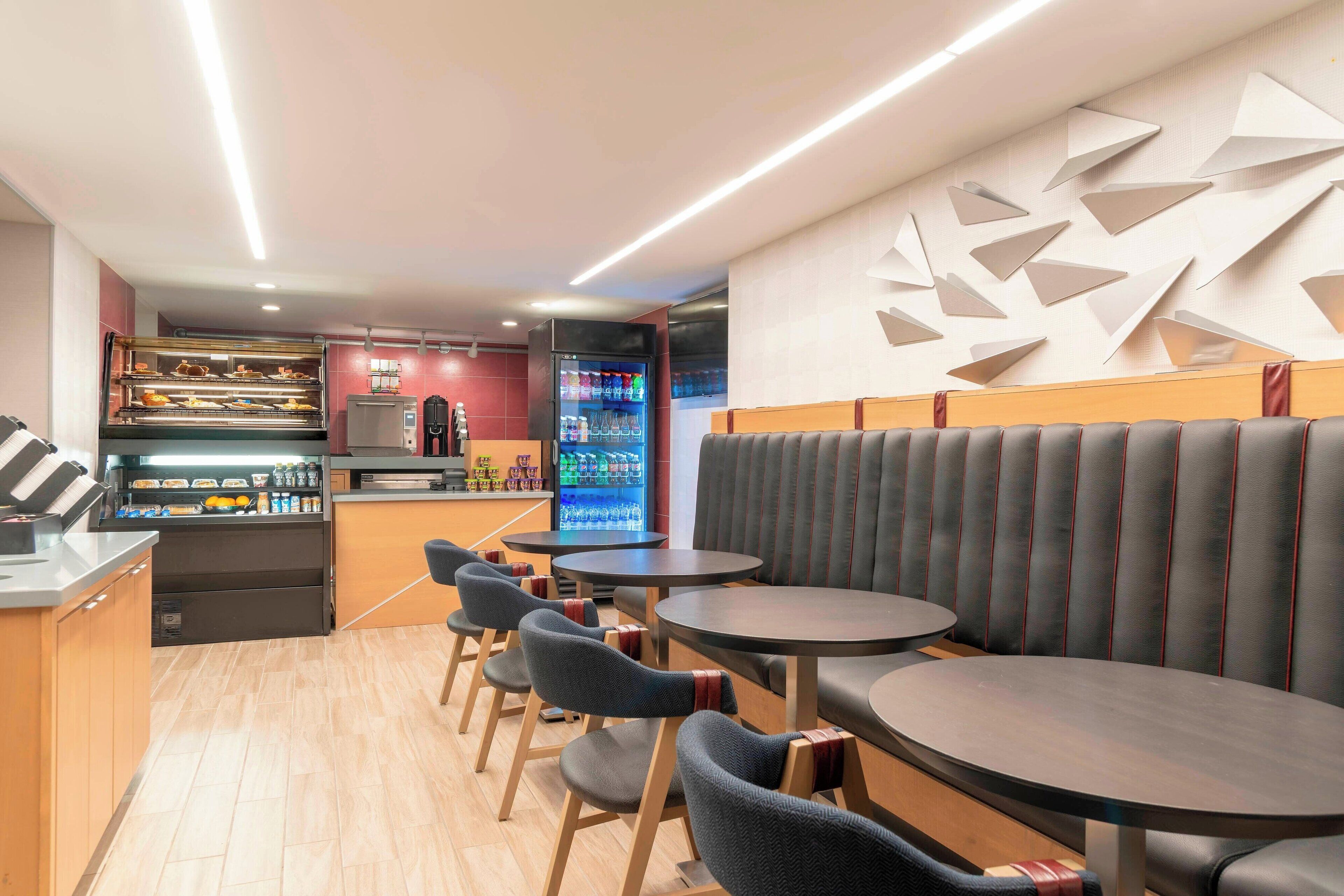 Un interior de restaurante moderno con asientos, una barra y un refrigerador.