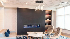 A modern living room with a sofa, two armchairs, a coffee table, and a fireplace. - Delta Hotels by Marriott Kalamazoo Conference Center (Kalamazoo)
