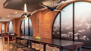A restaurant with a brick wall, large windows, and modern lighting fixtures. - Delta Hotels by Marriott Kalamazoo Conference Center (Kalamazoo)