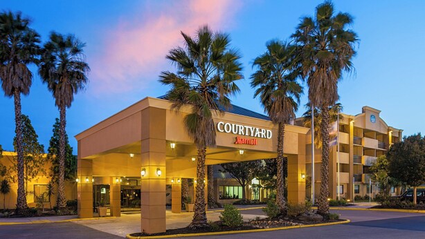 A Courtyard Marriott hotel with a modern design, featuring a large entrance, palm trees, and a well-lit facade. - Courtyard by Marriott Fairfield Napa Valley Area (Fairfield)