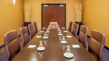 A conference room with a long table, brown leather chairs, and decorative plants.