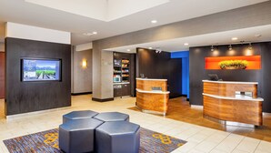 A modern reception area with a digital screen, a reception desk, and a seating area with ottomans. - Courtyard by Marriott Fairfield Napa Valley Area (Fairfield)