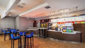 A modern bar area with blue bar stools, a counter with a menu, and a seating area with tables and chairs. - Courtyard by Marriott Fairfield Napa Valley Area (Fairfield)