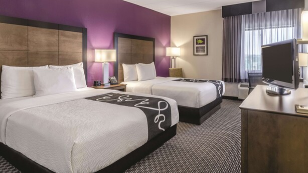 Une chambre d’hôtel avec deux lits, un bureau et une télévision.