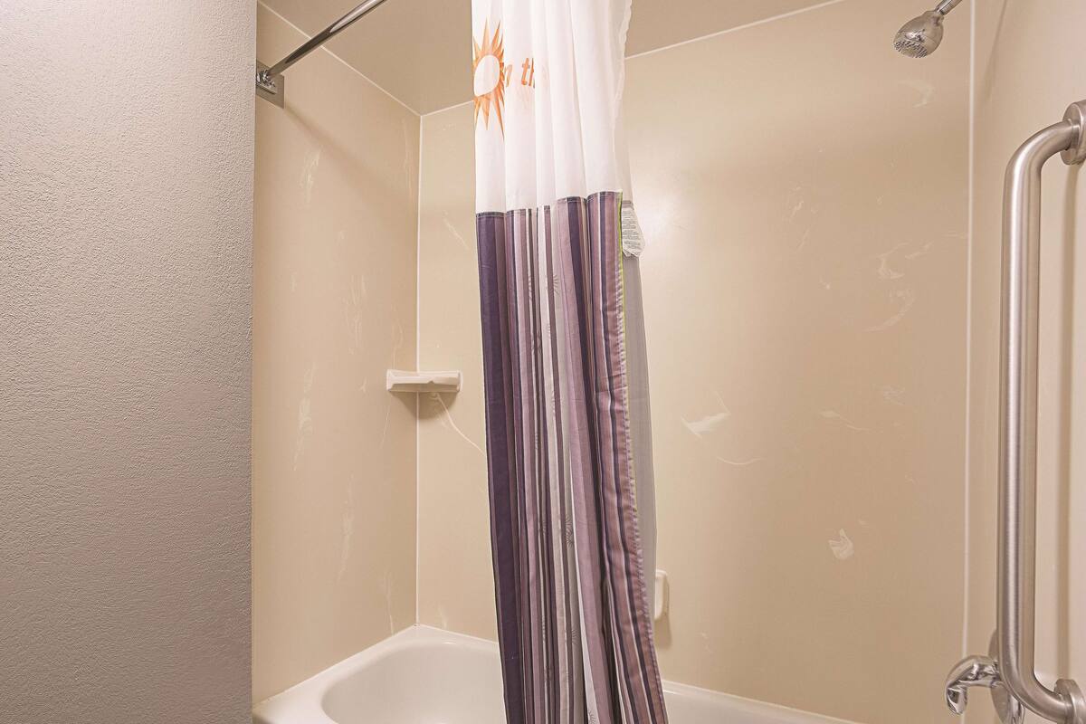 A bathroom with a bathtub, shower, and a curtain.