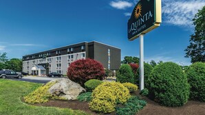 Une enseigne d’hôtel portant le nom « La Quinta Inn & Suites » et un bâtiment en arrière-plan.